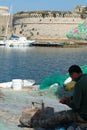 Morning landscape photo made in Gallipoli pier, fishermen reparing his fishermen net after fishing, Apulia, Italy