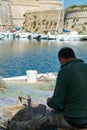 Morning landscape photo made in Gallipoli pier, fishermen reparing his fishermen net after fishing, Apulia, Italy