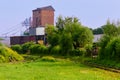 Morning landscape on the railway tracks. Sunbeams and a clearing of green grass between the rails. Red brick tower and Royalty Free Stock Photo