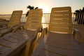 Morning landscape view of empty chaise lounges near swimming pool. Palm trees with blue sea in the background Royalty Free Stock Photo