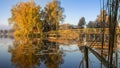 Morning landscape, wooden hunting lodge, on a small man-made island. A wooden platform is coming to the house, birch trees are