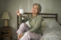 Morning lifestyle portrait of attractive and happy middle aged woman on her 50s having coffee on bed smiling relaxed and cheerful Royalty Free Stock Photo