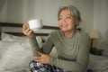 Morning lifestyle portrait of attractive and happy middle aged woman on her 50s having coffee on bed using internet mobile phone Royalty Free Stock Photo