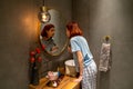 Millennial girl wearing pajamas standing in bathroom applying powder with brush before going out Royalty Free Stock Photo