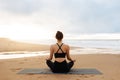 Morning meditation. Unrecognizable calm woman in activewear practicing yoga outdoors, sitting on beach near ocean Royalty Free Stock Photo