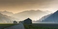 Morning mist in a mountain valley with fields and old wooden barns and lattice cross power lines and mountains in silhouette behin