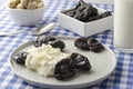 Closeup of plate with cottage cheese. prunes, peanuts on table. Delicious dieting dinner served on blue checkered tablecloth