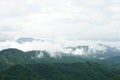 Morning mountain landscape with waves of fog and cloudy sky.