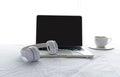 Morning music background. Coffee with laptop in white bed, sheet, duvet and pillow, messed up. Royalty Free Stock Photo