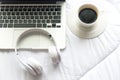 Morning music background. Coffee with laptop in white bed, sheet, duvet and pillow, messed up. Royalty Free Stock Photo