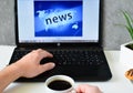 Morning news concept. Men`s hands hold a cup of morning coffee and click on the monitor buttons on a laptop, watching the news.