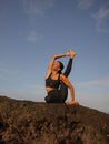 Morning outdoor yoga practice near the ocean. Asian woman practicing Eka Pada Sirsasana, Foot-behind-the-Head Pose. Flexible Royalty Free Stock Photo