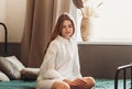 Morning portrait of a brooding young girl with long hair on a bed in the bedroom