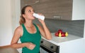 Morning portrait of young woman drinking whey protein beverage. Home fitness girl drinks kefir from bottle