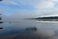 Morning river fisherman on a boat, blue sky clouds reflected in the smooth Royalty Free Stock Photo