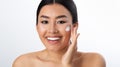 Morning routine. Asian girl applying cream on cheeks Royalty Free Stock Photo