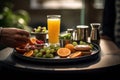 A morning routine scene with a person holding a tray of breakfast items, featuring a prominently placed glass of orange juice,