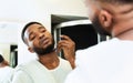 Young black man shaving beard, looking at bathroom mirror Royalty Free Stock Photo