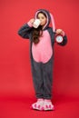 Morning routines. Adorable bunny hold alarm clock. Small girl in bunny costume. Child rabbit kigurumi. Girl bunny Royalty Free Stock Photo