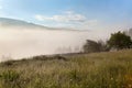 Wooden fence across meadow, fog gy mountains on the background. Ukraine, Carpathians. Royalty Free Stock Photo