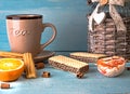 Morning scene with cup of tea or coffee, Dutch cookie stroopwafel, Delfts blue souvenir, on blue table