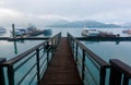 Morning scenery of sightseeing boats moored to the floating docks of a wooden pier & foggy mountains by lakeside