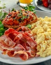 Morning Scrambled egg, bacon breakfast with beans in tomato sauce on toasted bread on white plate