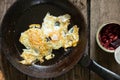 Morning scrambled eggs in a frying pan with beans on a wooden table