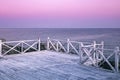 Morning seascape. Calm sea, wooden bridge on a background of pink dawn sky Royalty Free Stock Photo