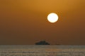 Seascape with silhouette of a pleasure ship and disk of the sun in the red sky Royalty Free Stock Photo