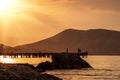 Morning seascape. Silhouettes of fishermen on the pier in the rays of the morning sun. Royalty Free Stock Photo