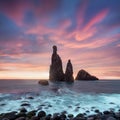 Morning seascape sunrise of Madeira. Rocky shore, silhouette of two steep cliffs and misty rocks hit by waves. Long exposure.