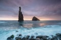 Morning seascape sunrise of Madeira. Rocky shore, silhouette of two steep cliffs and misty rocks hit by waves. Long exposure.