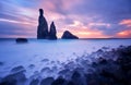 Morning seascape sunrise. Rocky shore, rounded boulders, silhouette of two steep cliffs and rocks. Long exposure, mist effect.