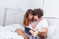 Morning selfie. Young happy beautiful couple on the bed making self portrait by smartphone and hugging, Couple on Bed Taking Sweet Royalty Free Stock Photo