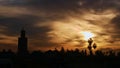 Morning sky with bright sun above the old center of Marrakesh, Morocco with silhouettes of roofs, palm trees and a minaret tower. Royalty Free Stock Photo