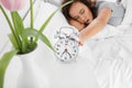 Morning of sleepy young African-American woman turning off alarm clock while lying in bed Royalty Free Stock Photo