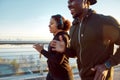 Morning sport. Young smiling african couple in headphones jogging together on the bridge. Happy African man and woman Royalty Free Stock Photo