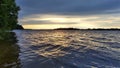 In the morning, the sun rises over the lake and colors the clouds in the sky. A forest stands on the shores, reeds grow in the wat Royalty Free Stock Photo