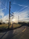 Morning Sun Shine over Field of power lines at the end of a Country road Royalty Free Stock Photo