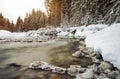 Morning sun shines on forest river creek in winter, rocks on shore covered with snow, long exposure makes water silky smooth