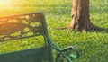 Sunlight on backrest surface of the old empty metal park bench on green lawn in public park area Royalty Free Stock Photo