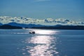 The morning sunlight mapped the surface of the lake. The work boat is operating.