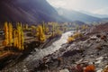 Colorful trees in autumn with shiny Gilgit river against Hindu Kush mountain range Royalty Free Stock Photo