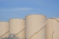 Morning sunlight on surface of white storage fuel tanks group against blue sky in petroleum industrial area Royalty Free Stock Photo