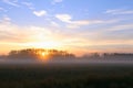 Early Morning Sunrise over a Farm Field with Heavy Mist on the Grass and Trees. Royalty Free Stock Photo
