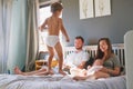 Morning time is bonding time. a little boy jumping on the bed while his family relaxes together. Royalty Free Stock Photo