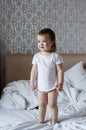 Portrait of a cute baby girl on white bed in ligth interior. Good Morning