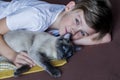 Cute handsome blonde boy lying in  bed and playing with cat. Relax time Royalty Free Stock Photo