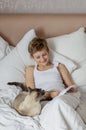 Cute handsome blonde boy lying in white bed. Boy smiling and playing with cat. Relax time Royalty Free Stock Photo